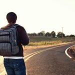 Solo traveler with a backpack looking at a breathtaking view, representing freedom, self-discovery, and smart ways to find solo travel deals.