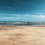 Sun-drenched shoreline of a beautiful Texas beach with calm, blue-green water, illustrating a perfect coastal vacation on the Gulf Coast.