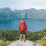 Backpacker enjoying a breathtaking view, illustrating the concept of affordable world travel and budget-friendly adventures.