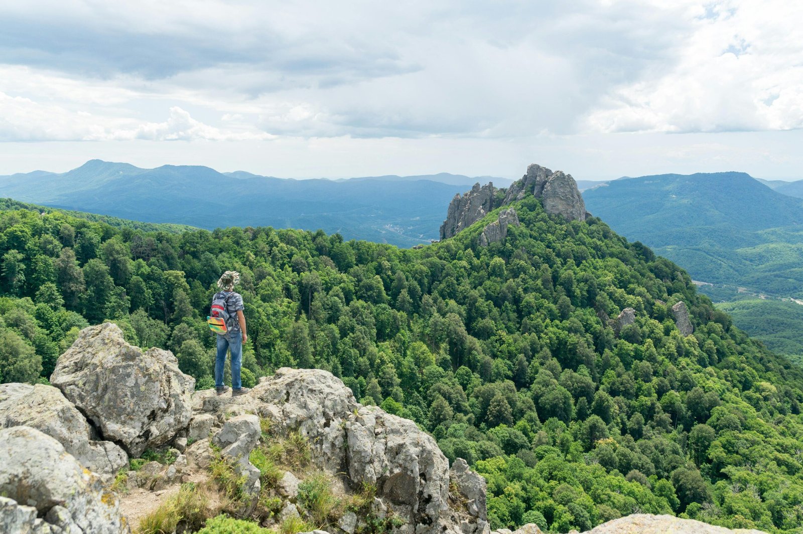 A solo traveler, seen from behind, stands on a scenic viewpoint overlooking a vast landscape, symbolizing freedom and self-discovery on an independent travel adventure.
