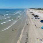 South Padre Island beach scene with families enjoying the sand and ocean, symbolizing new eco-friendly attractions, events, and improved visitor experience for 2025.