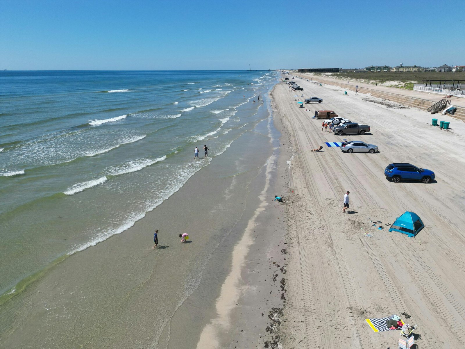 South Padre Island beach scene with families enjoying the sand and ocean, symbolizing new eco-friendly attractions, events, and improved visitor experience for 2025.