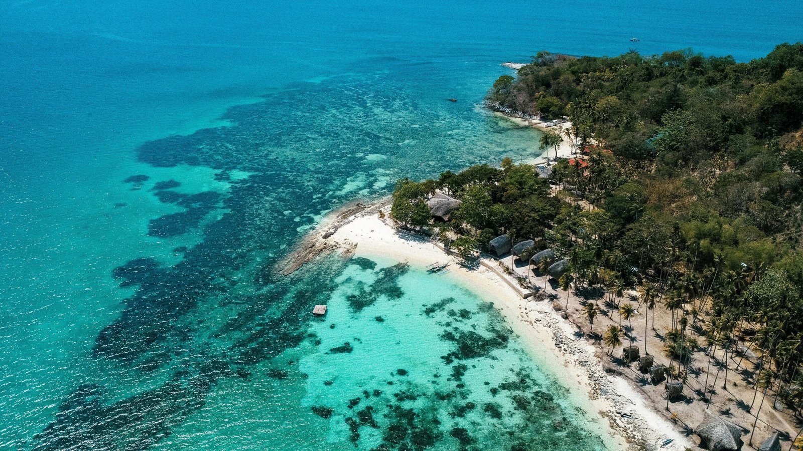 Aerial view of a beautiful tropical island paradise with a white sand beach and turquoise ocean, illustrating the best island to visit for a 2025 vacation getaway.