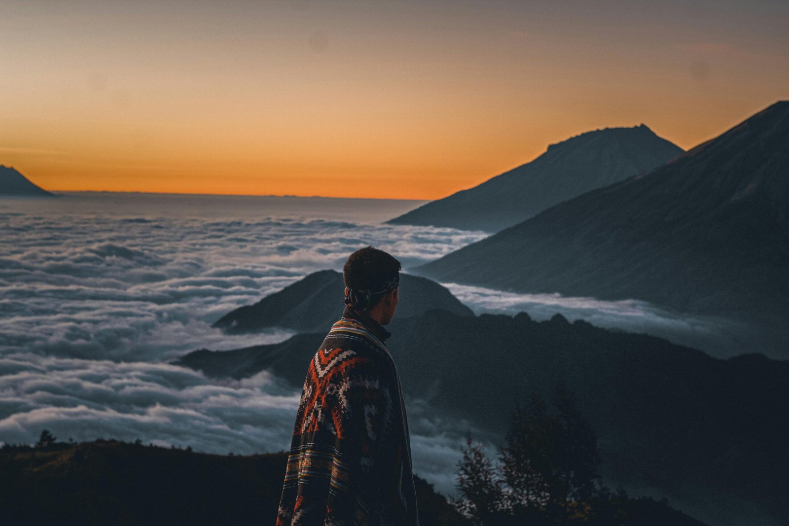 A solo traveler with a backpack looks out over a vast mountain landscape, illustrating the freedom and self-discovery of a well-planned solo travel journey.