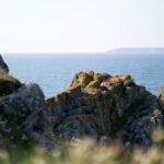 A traveler looking out over a beautiful, sunny coastline, an example of the best place to travel in May for a perfect spring holiday.