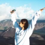 Empowered woman traveler stands confidently in a scenic landscape, symbolizing freedom, self-discovery, and adventure in solo female travel.