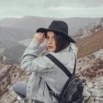 A female solo traveler with a backpack looks out over a vast mountain range, embodying the freedom and adventure of a solo travel experience.