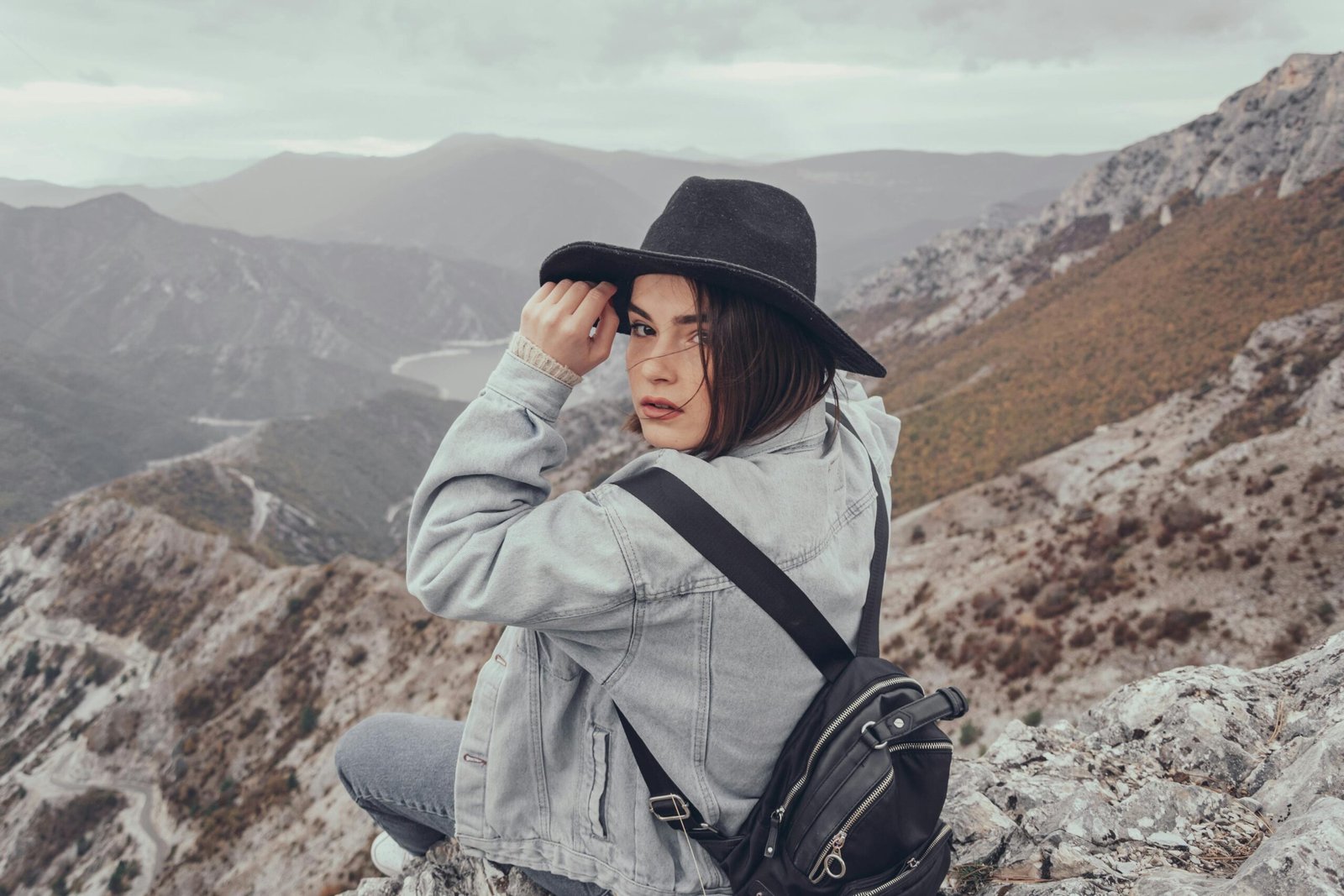 A female solo traveler with a backpack looks out over a vast mountain range, embodying the freedom and adventure of a solo travel experience.