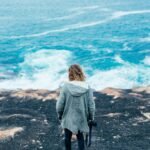 Empowered solo female traveler admiring a vast scenic landscape, illustrating safe and inspiring travel destinations for women.