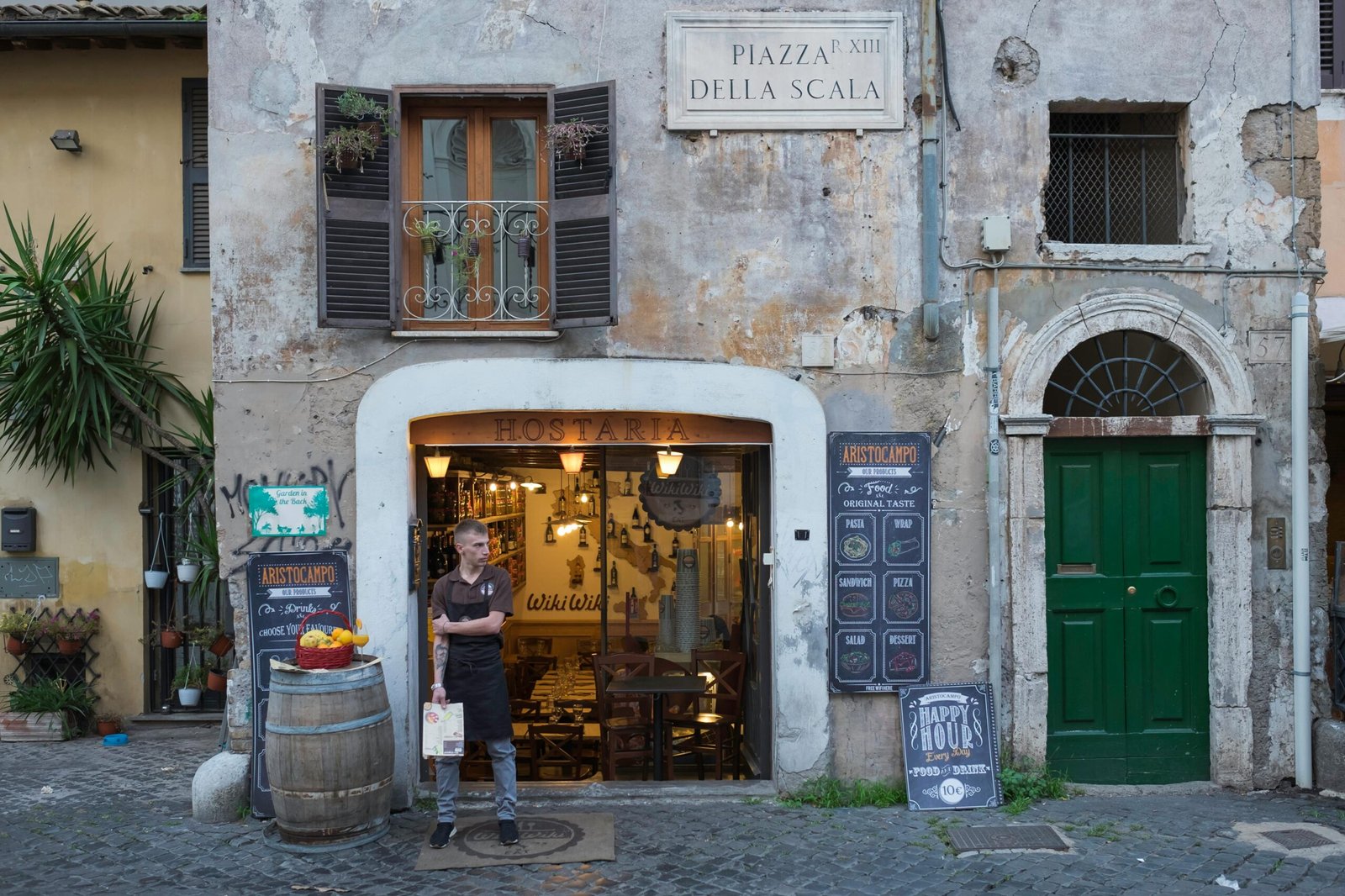 A charming, narrow cobblestone street in the Trastevere district of Rome, one of the city's most touristy areas, shown in the peaceful morning light without crowds.