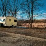 Winterizing a travel trailer: A person pours RV antifreeze into the plumbing system to protect pipes from freezing and prevent damage during cold winter months.